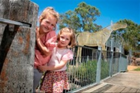 Two children smiling and looking at the camera while playing in the park