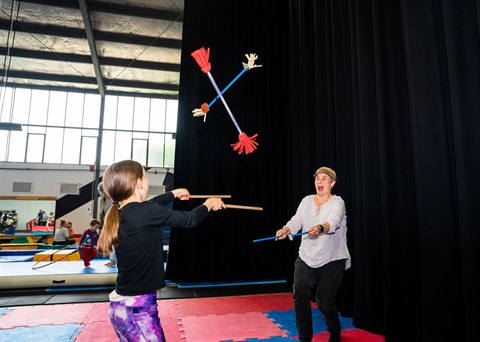 Two girls practice juggling and throwing batons.