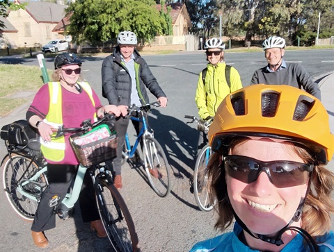 A group of cyclists pauses for a photo, showcasing their safety gear and bicycles.