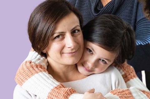 A mom hugs her smiling child..