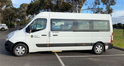 A large bus parked in an empty parking lot that community groups can hire