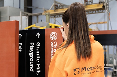 Employee working on an outdoor information sign assembly, noting the 