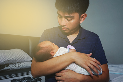 A parent looks at the baby in their arms.