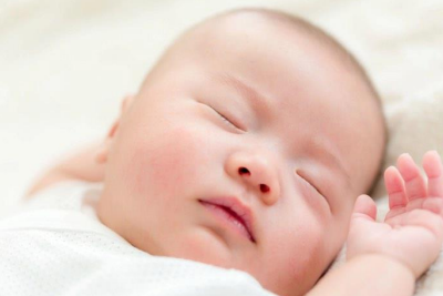 A baby lies on its back asleep.