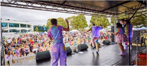 Four performers dance on stage in front of a festival crowd.