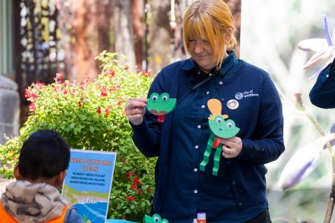 Volunteer engages children with interactive frog puppet display.