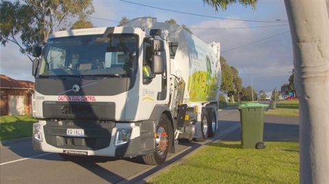 A white garbage truck, meticulously designed, navigates a residential street, collecting the day's refuse. 