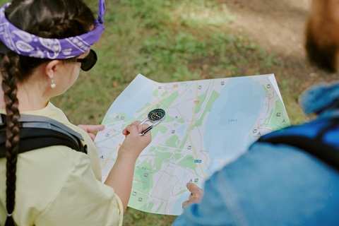 Young girl with purple bandana and male teacher looking at a map with a compass
