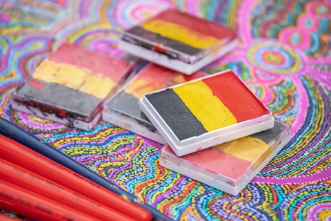 close up of craft activities, paint pallets with aboriginal flag colours (black, yellow, red)